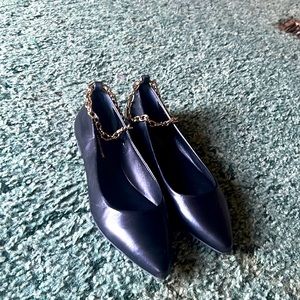 Pointed toe black flats with a golden anklet chain.